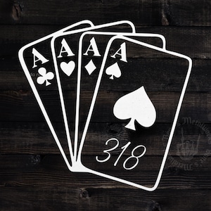 May include: White metal art piece featuring four playing cards, all aces, against a dark wood background. The cards display the suits of clubs, hearts, diamonds, and spades. The number 318 is also visible on one card.