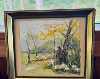 May include: A framed watercolor painting depicting a shepherd with a flock of sheep in a green field. The scene is set in a forest with trees and foliage in shades of green, yellow, and brown. The painting is signed in the bottom left corner.
