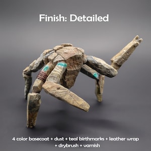 May include: A multi-legged stone-like creature figurine with a textured tan and brown surface. It features teal accents, a copper-colored wire wrap on one limb, and the text Finish: Detailed and 4 color basecoat + dust + teal birthmarks + leather wrap + drybrush + varnish.
