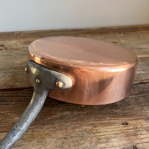 May include: A copper saucepan with a long, silver handle. The saucepan has a hammered finish and is in good condition.
