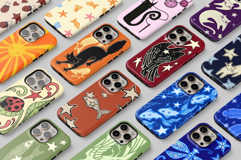 May include: A collection of smartphone cases featuring diverse graphic patterns including ladybugs, cats, fish, stars, and celestial motifs in various colors such as orange, red, blue, green, and purple, each with a triple camera lens cutout.