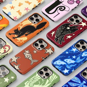 May include: A collection of smartphone cases featuring diverse graphic patterns including ladybirds, cats, fish, stars, and celestial motifs in various colours such as orange, red, blue, green, and purple, each with a triple camera lens cutout.