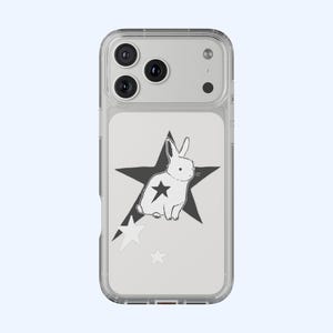 May include: Clear phone case featuring a white rabbit illustration inside a black star, with additional white star accents. The case has a clear border and a light blue background. The design is simple and graphic.