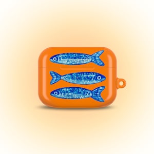 May include: A bright orange protective case for wireless earbuds featuring a horizontal pattern of three blue fish. The case has a rectangular shape with rounded corners, a hinged lid, and a small circular loop on the right side for attachment.