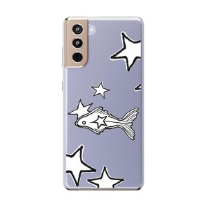Puede incluir: Funda transparente para tel&eacute;fono con fondo lavanda que presenta un patr&oacute;n de estrellas blancas y una ilustraci&oacute;n de pez. La funda del tel&eacute;fono tiene un m&oacute;dulo de c&aacute;mara y botones dorados.