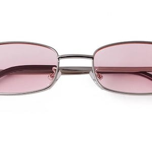 May include: Rectangular-framed sunglasses with a silver metal frame and pink lenses. The temples are black. The glasses are displayed on a white background.