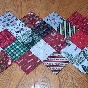 May include: A festive Christmas table runner with a patchwork design. The runner showcases various seasonal patterns, including red trucks, snowmen, Christmas trees, and plaid. The squares are arranged in a diamond pattern, creating a decorative holiday piece.