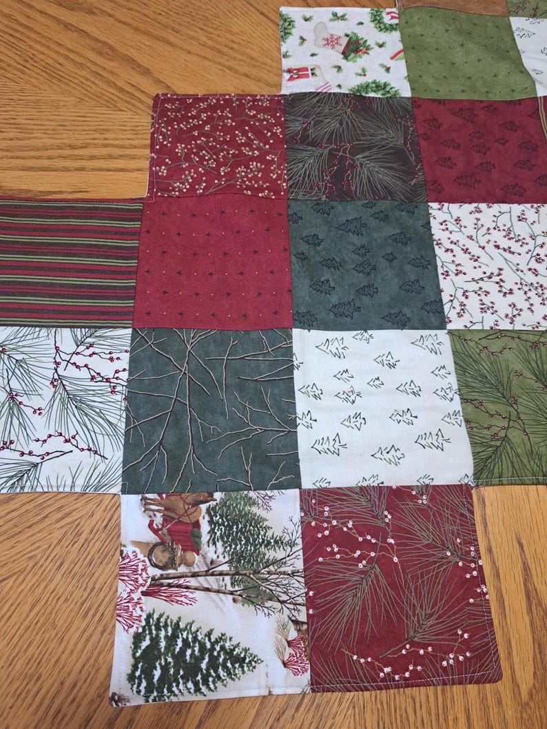 Pu&ograve; includere: Un runner da tavolo natalizio patchwork con vari motivi festivi. I quadrati presentano strisce rosse e verdi, aghi di pino, alberi di Natale e motivi floreali. Il runner &egrave; realizzato in tessuto ed &egrave; progettato per le festivit&agrave;.