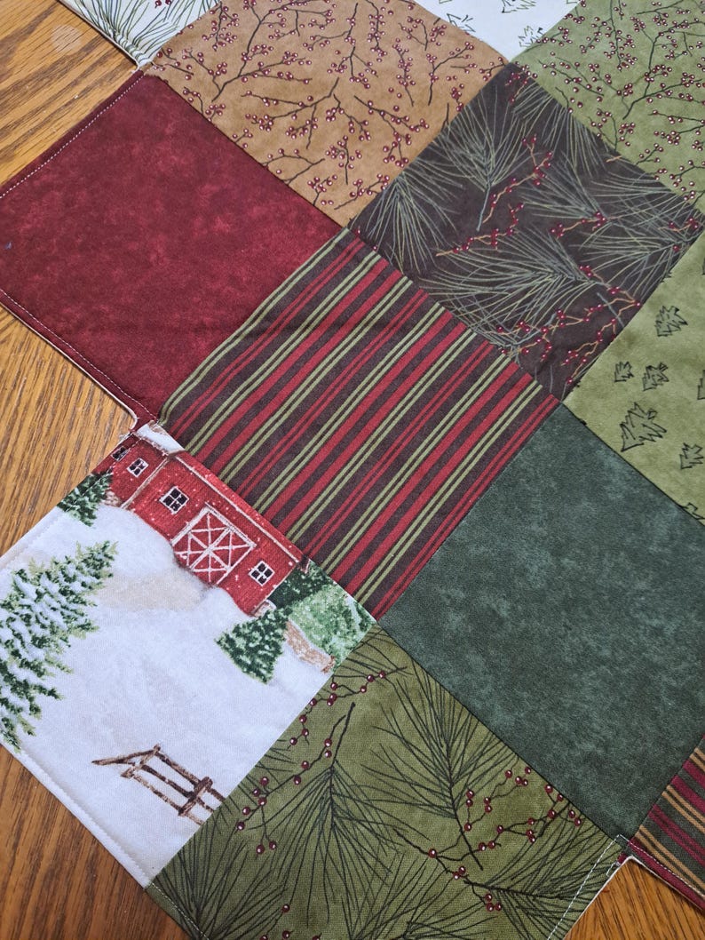 Pu&ograve; includere: Una tovaglia natalizia patchwork con vari motivi di tessuto. Il design include quadrati di tessuti rossi, verdi, marroni e bianchi. Alcuni quadrati presentano strisce, aghi di pino o una scena di fattoria invernale. La tovaglia &egrave; probabilmente in cotone.