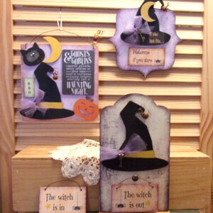 Puede incluir: Cuatro decoraciones de Halloween de madera con sombreros de bruja, calabazas y arañas. Los letreros dicen "Ghosts & Goblins", "Welcome if you dare", "The witch is in" y "The witch is out".