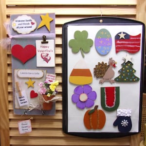 May include: A gray wooden wall organizer with a heart, star, and floral accents, featuring text including Welcome family and friends, Happy Valentine's, and Home Sweet Home, alongside a black metal tray displaying seasonal magnetic shapes.