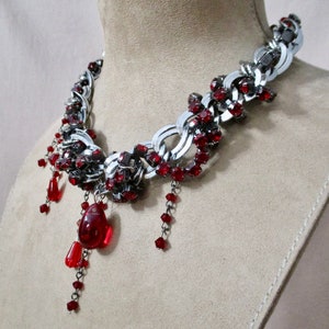 Puede incluir: Un collar de cadena plateada con detalles de cristal rojo y cristales de l&aacute;grima rojos colgantes.