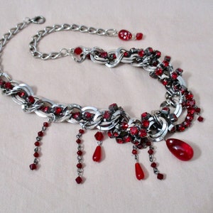 Puede incluir: Un collar de cadena de plata con acentos de pedrer&iacute;a roja. El collar tiene un dise&ntilde;o colgante con m&uacute;ltiples hebras de cuentas rojas.