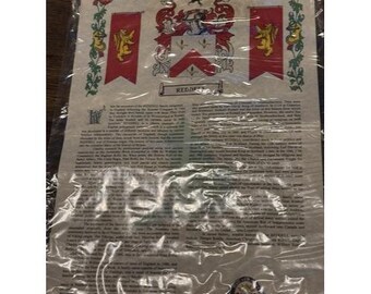 May include: A parchment-style document featuring a family crest with red and gold accents, displayed within a clear plastic sleeve. The crest includes a shield, helmet, and banner, with the name "REDDE" visible. The document is filled with text.