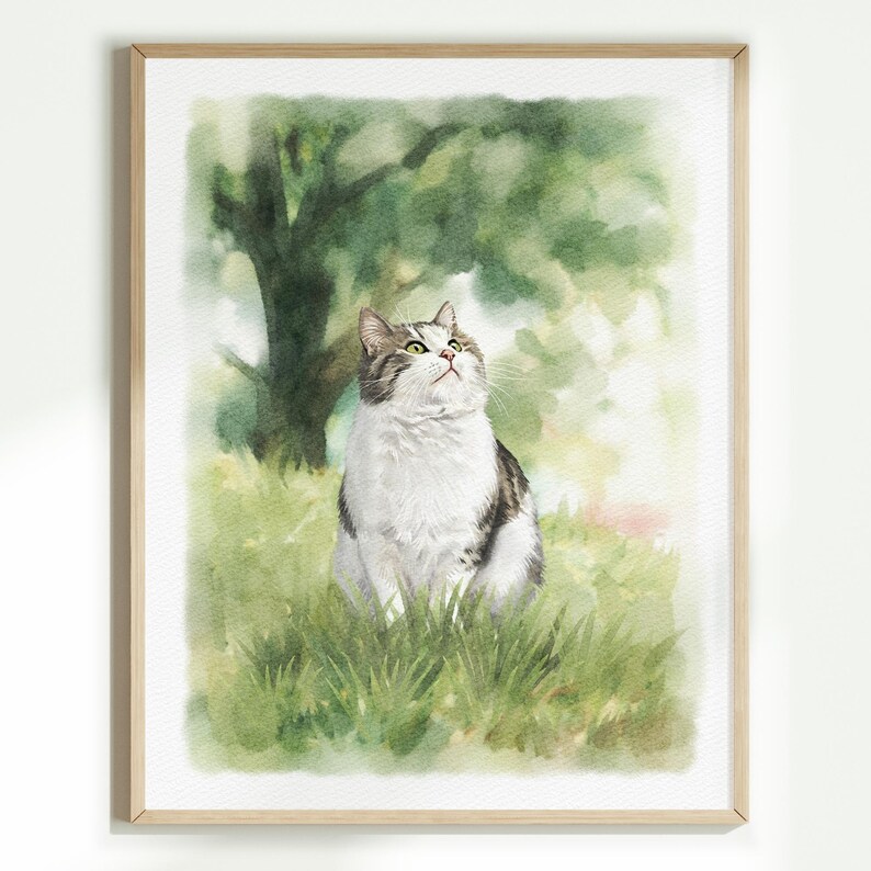 K&ouml;nnte beinhalten: Ein Aquarellbild einer grau-wei&szlig;en getigerten Katze, die in einer gr&uuml;nen Wiese sitzt. Die Katze schaut mit geneigtem Kopf nach oben. Der Hintergrund zeigt einen weichen, verschwommenen gr&uuml;nen Baum und Laub in einem hellen, luftigen Kunststil.