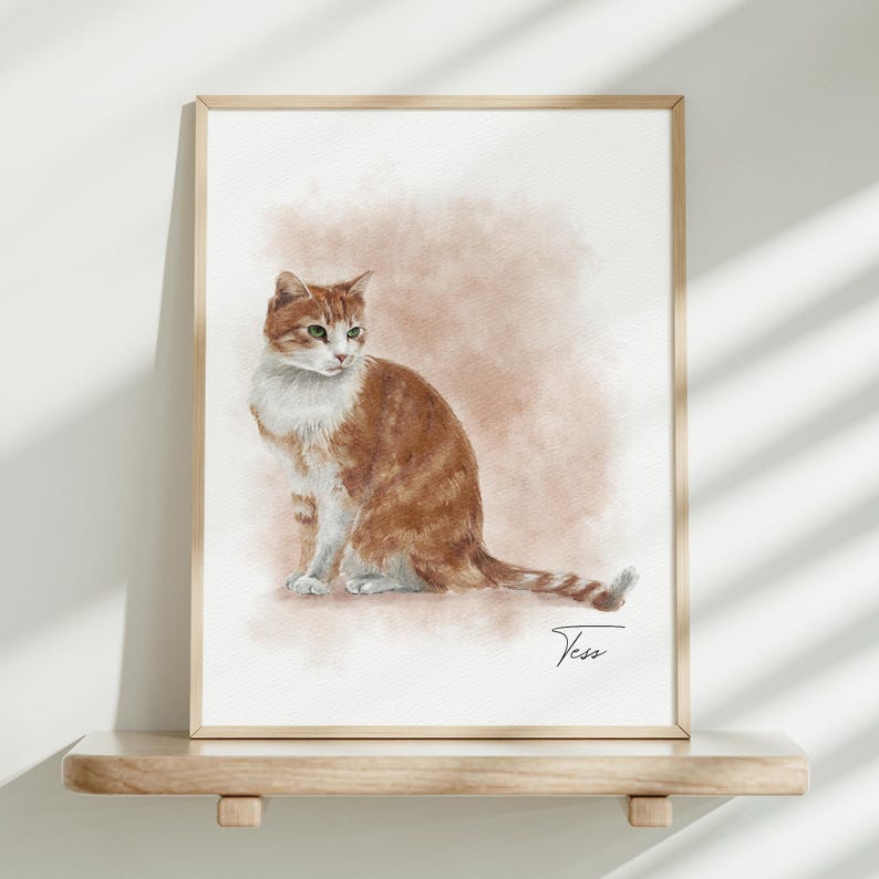 K&ouml;nnte beinhalten: Ein gerahmtes Aquarellbild einer rot-wei&szlig;en Katze, die im Profil sitzt. Die Katze hat gr&uuml;ne Augen und einen gestreiften Schwanz. Der Hintergrund ist ein weicher, ged&auml;mpfter beiger Farbverlauf. Der Name Tess steht in schwarzer Schreibschrift unten rechts.