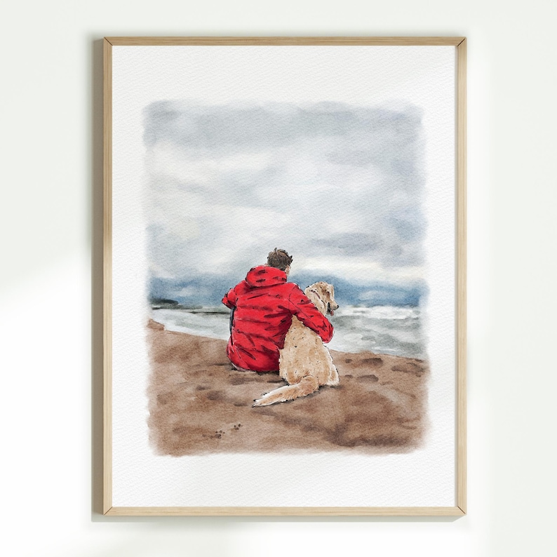 May include: Watercolour painting of a person in a red jacket with a golden retriever dog, sitting on a sandy beach, looking out at the ocean under a cloudy sky. The artwork is framed in a light wood frame.