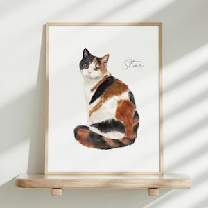 K&ouml;nnte beinhalten: Ein gerahmter Aquarelldruck eines dreifarbigen Katzenbildes mit schwarzem, orangefarbenem und wei&szlig;em Fell, das sitzt und den Betrachter ansieht. Die Katze hat bernsteinfarbene Augen und eine rosa Nase. Rechts neben der Katze steht das Wort Star in schwarzer Schreibschrift.