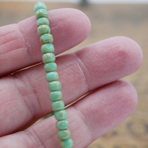 May include: A strand of light green glass beads with a faceted, hexagonal shape.