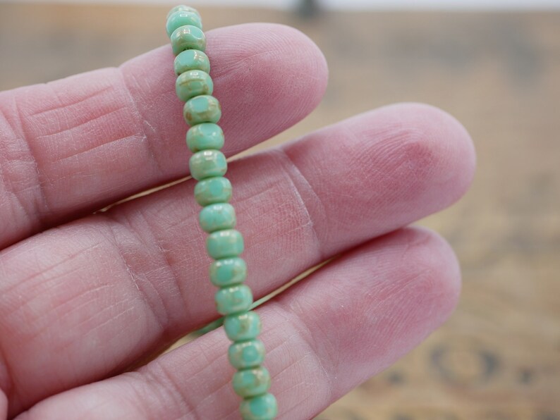 May include: A strand of light green glass beads with a faceted, hexagonal shape.