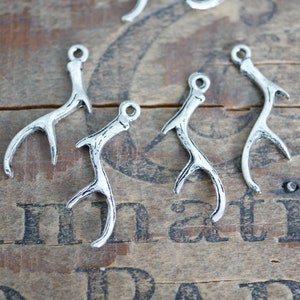 May include: Five silver-toned metal deer antler charms. The charms are shaped like a single antler with a loop at the top for attaching to jewelry or other crafts.