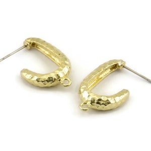 May include: A pair of gold-toned hammered hoop earrings with a textured finish. The earrings have a simple, modern design and are perfect for everyday wear.