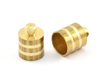 Puede incluir: Dos tapones de extremo de metal de color dorado con forma cilíndrica lisa y una banda decorativa alrededor del centro. Los tapones tienen un pequeño bucle en la parte superior para sujetarlos a un cordón o cadena.
