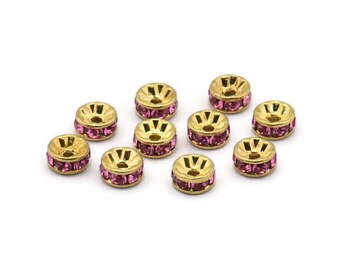 May include: A collection of ten gold-colored spacer beads with a ring of pink rhinestones. Each bead has a unique design on the top. These beads are ideal for jewelry making and crafting projects.