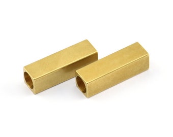 May include: Two gold-colored metal bar spacers with a hollow center. The spacers are rectangular in shape and have a smooth, polished finish.