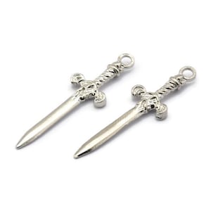 May include: Two silver sword charms with intricate details. The swords have a twisted design and a cross-shaped hilt.