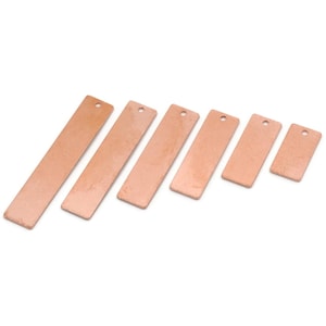 May include: Six rectangular, copper-colored metal tags of varying sizes, each with a small hole at the top. The tags are arranged diagonally against a white background, showcasing their smooth, reflective surfaces. Ideal for jewelry making or crafting.