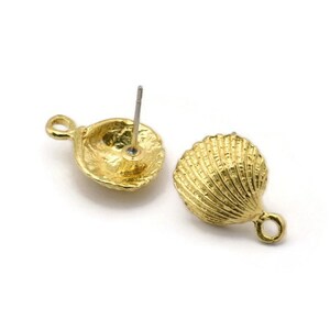 Op de afbeelding: Een paar gouden oorknopjes in de vorm van een schelp met een lus aan de ene kant en een pen aan de andere.