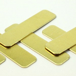 May include: A group of five rectangular brass plates stacked on top of each other. The plates are smooth and have a slightly rounded edge.