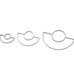 May include: Three silver-coloured, geometric pendants. Each pendant has a circular element connected to a semi-circular base. The sizes vary, with the largest measuring approximately 5 cm across.