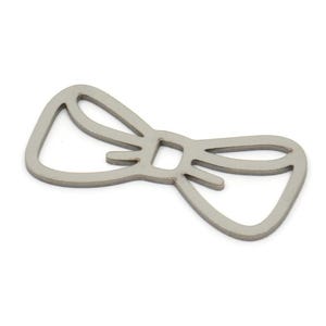 Op de afbeelding: Een zilveren metalen bedel in de vorm van een strikje.
