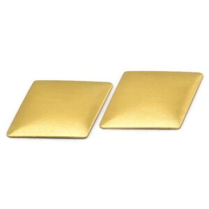 Puede incluir: Dos pendientes de color dorado en forma de diamante.