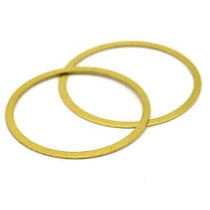 Puede incluir: Dos anillos de metal de color dorado, uno ligeramente más grande que el otro, están apilados uno encima del otro.