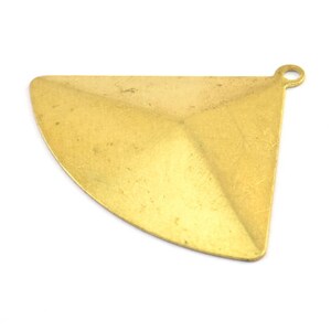 Peut inclure: Un pendentif en métal doré en forme de triangle avec un bord inférieur arrondi. Le pendentif a une petite boucle en haut pour attacher une chaîne ou un cordon.