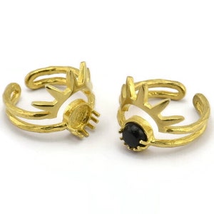May include: Two gold adjustable rings with a sunburst design. One ring has a black gemstone in the center.