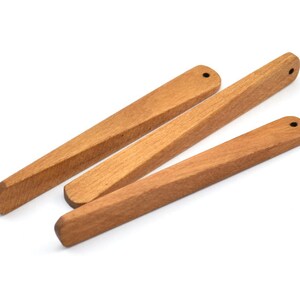 May include: Three wooden kitchen utensils with rounded ends. The utensils are made of light brown wood and have a smooth finish.