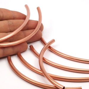 May include: A set of six copper pipe segments, each bent into a half-circle shape. The segments are arranged in a fan-like pattern, with the ends of the segments overlapping.