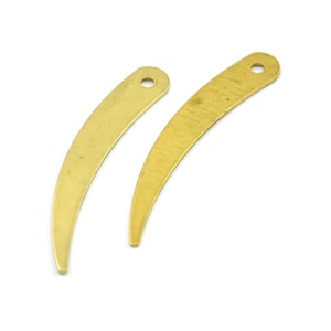 May include: Two gold-colored metal crescent-shaped charms with a hole at the top.