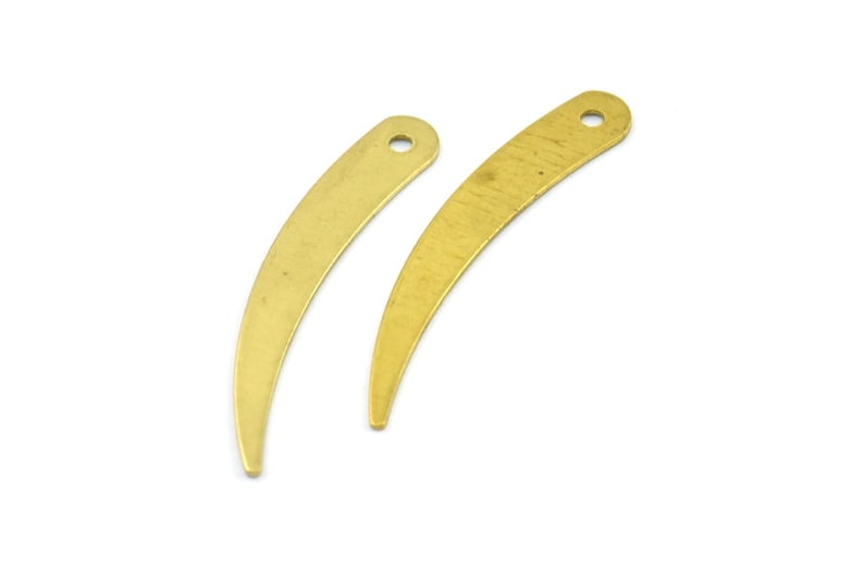 May include: Two gold-colored metal crescent-shaped charms with a hole at the top.