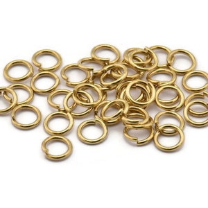 May include: A pile of gold jump rings, a type of jewelry finding used for connecting chains, cords, and other jewelry components.