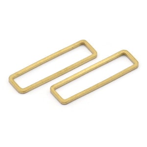 Puede incluir: Dos anillos de salto rectangulares de metal de color dorado. Los anillos están abiertos y tienen un acabado liso.