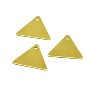 Peut inclure: Trois breloques triangulaires dorées avec un trou en haut. Les breloques sont plates et ont une surface légèrement texturée.