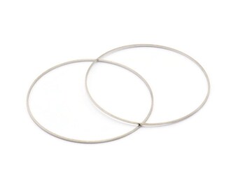 May include: Two silver metal hoops, one slightly larger than the other, are stacked on top of each other.