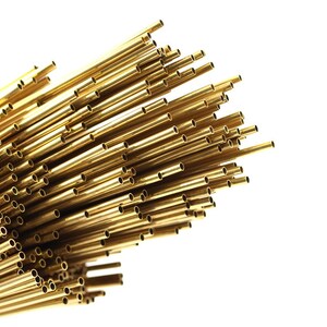 May include: A bundle of shiny gold brass tubing, arranged in a fan shape, with the ends of the tubes visible.
