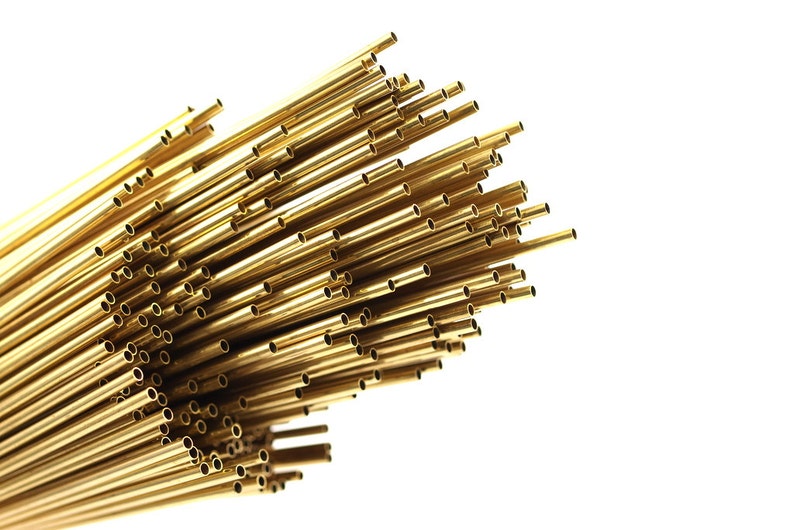 May include: A bundle of shiny gold brass tubing, arranged in a fan shape, with the ends of the tubes visible.