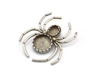 May include: Silver spider pendant with two round, open-backed bezels for adding a cameo or other embellishment.